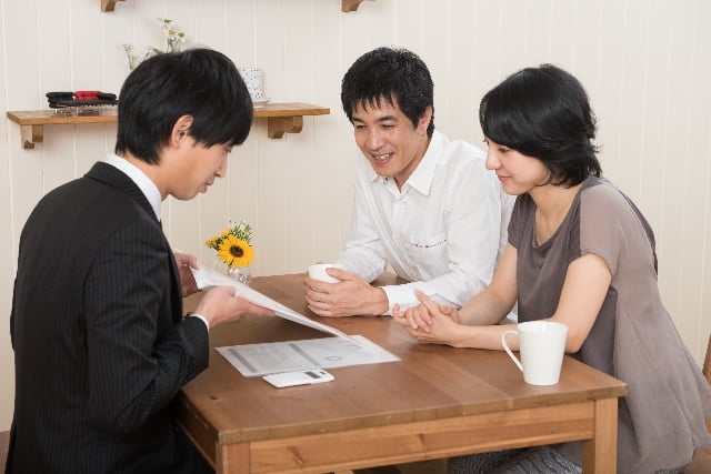 書類を使って説明する男性と説明を聞く男女